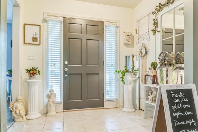 foyer entrance featuring tile patterned flooring, plenty of natural light, and ornate columns