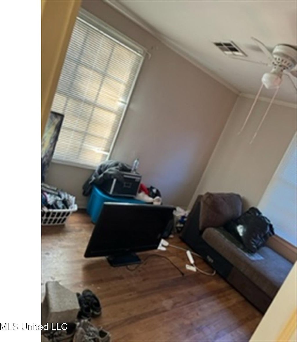 interior space with ceiling fan, wood-type flooring, and ornamental molding