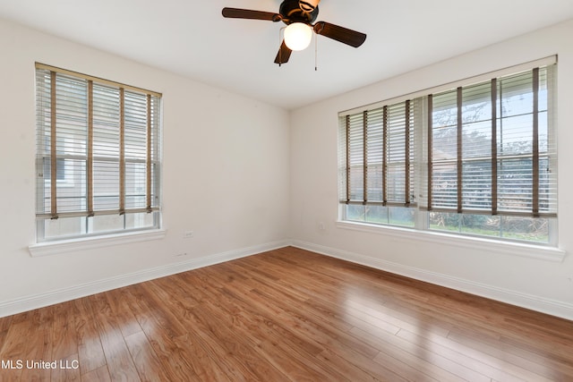 unfurnished room with wood finished floors, a ceiling fan, and baseboards