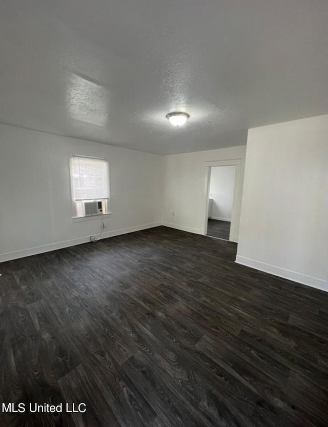 empty room featuring a textured ceiling, cooling unit, and dark hardwood / wood-style floors