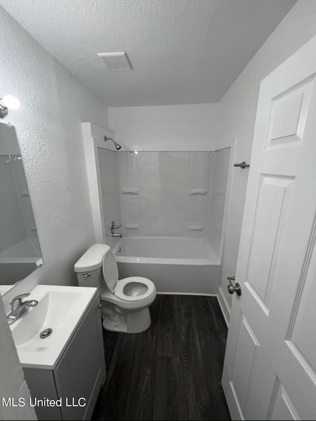 full bathroom featuring shower / bathing tub combination, a textured ceiling, wood-type flooring, toilet, and vanity