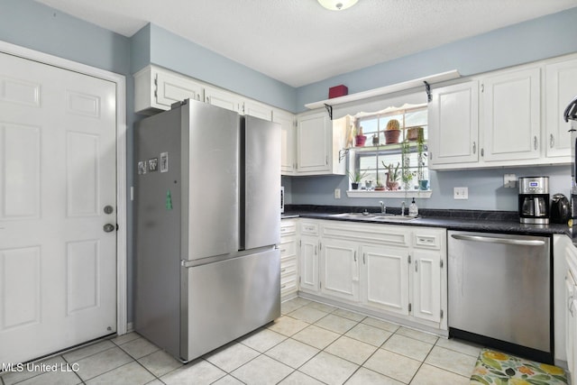 kitchen with white cabinets, stainless steel appliances, dark countertops, and a sink