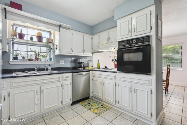 kitchen featuring oven, dark countertops, a sink, dishwasher, and a textured ceiling