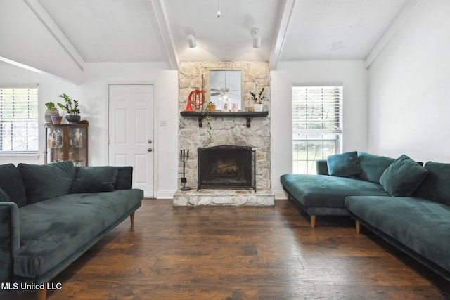 living area featuring a stone fireplace, beam ceiling, a wealth of natural light, and wood finished floors