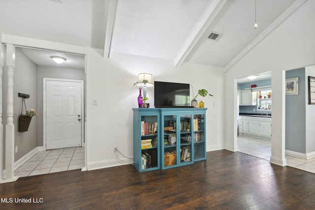 interior space featuring baseboards, lofted ceiling with beams, wood finished floors, and visible vents