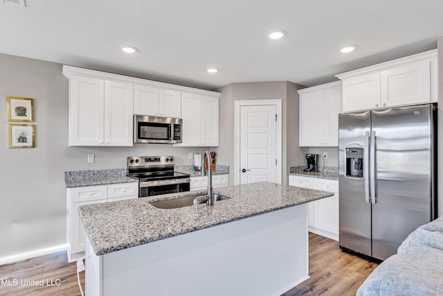 kitchen featuring a kitchen island with sink, sink, stainless steel appliances, and white cabinets