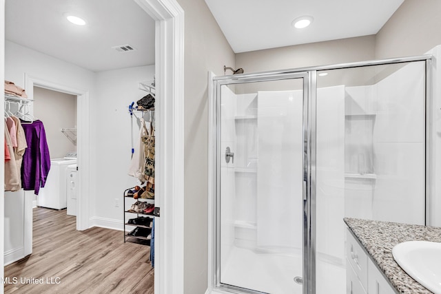 bathroom with vanity, wood-type flooring, washing machine and dryer, and walk in shower