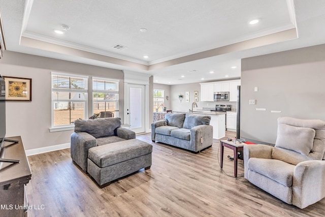 living room featuring a wealth of natural light, ornamental molding, and a raised ceiling