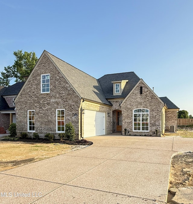 4263 S Bolivar Trl, Olive Branch, MS 38654 - view of front of house featuring brick siding, driveway, an attached garage, roof with shingles, and central air condition unit