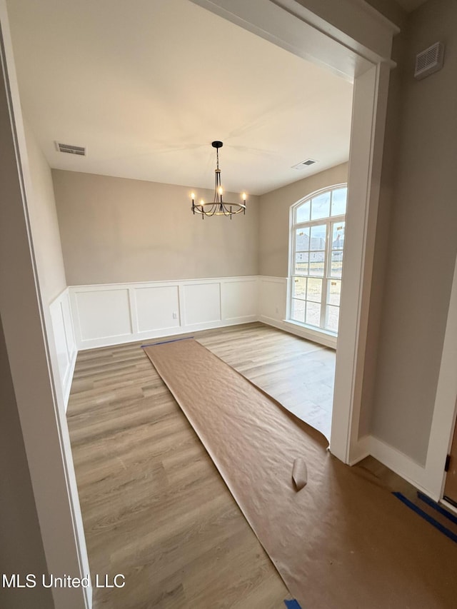 4263 S Bolivar Trl, Olive Branch, MS 38654 - unfurnished dining area with light wood-style flooring, wainscoting, and a chandelier