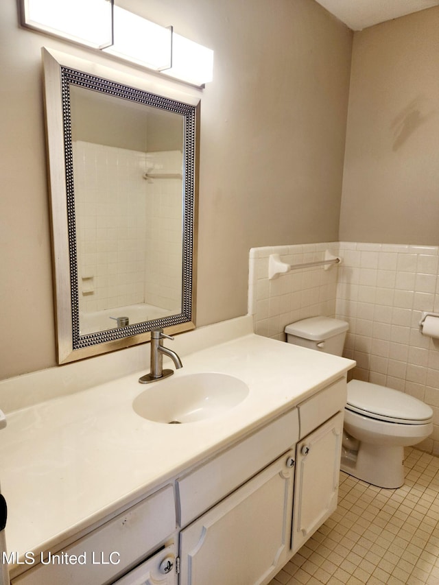 bathroom featuring tile walls, vanity, toilet, and tile patterned flooring