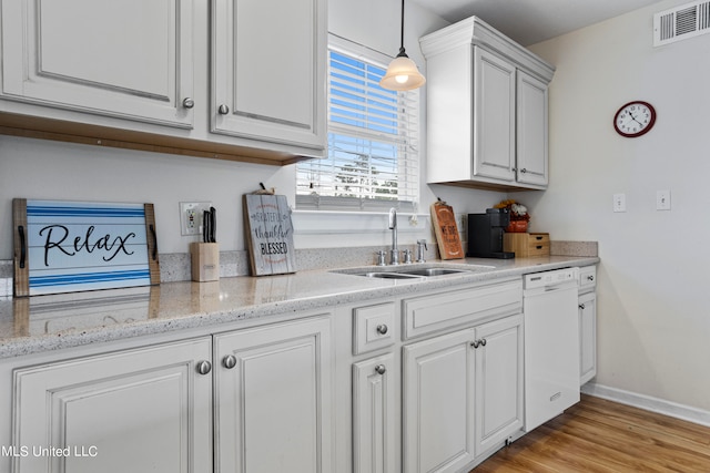 kitchen featuring dishwasher, light wood-type flooring, sink, hanging light fixtures, and white cabinets