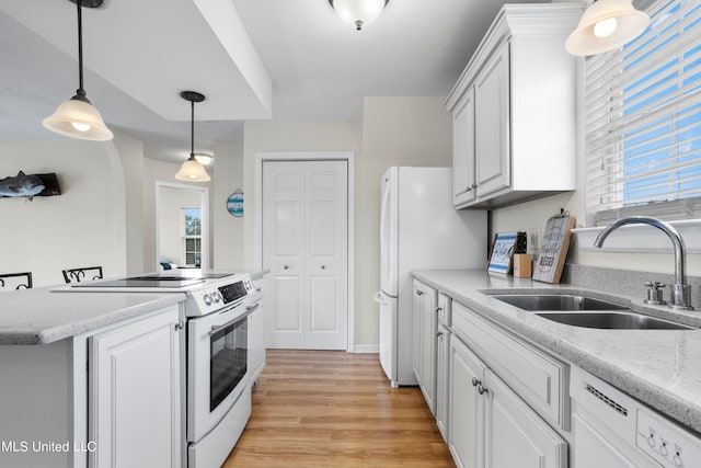 kitchen with white appliances, sink, hanging light fixtures, white cabinetry, and light hardwood / wood-style flooring