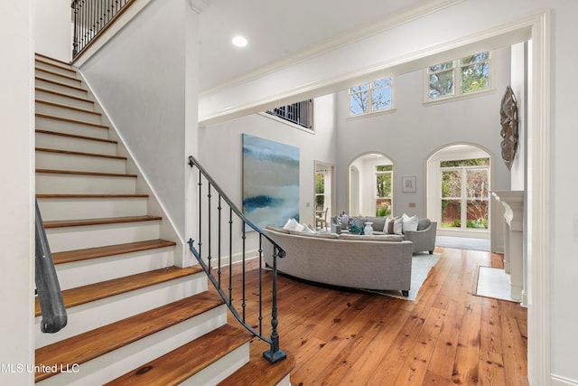 living room with a high ceiling, wood-type flooring, and ornamental molding