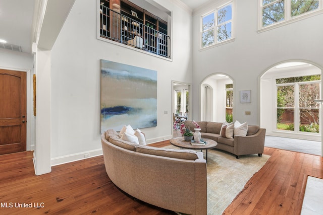 living room with hardwood / wood-style floors, a wealth of natural light, a high ceiling, and crown molding