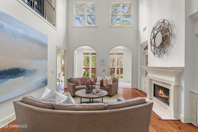 living room featuring a high ceiling, a premium fireplace, and light hardwood / wood-style flooring