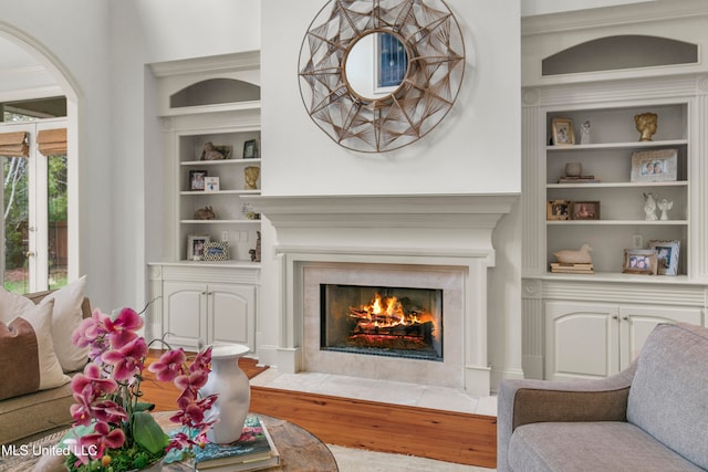 living room featuring built in shelves, hardwood / wood-style floors, and a fireplace