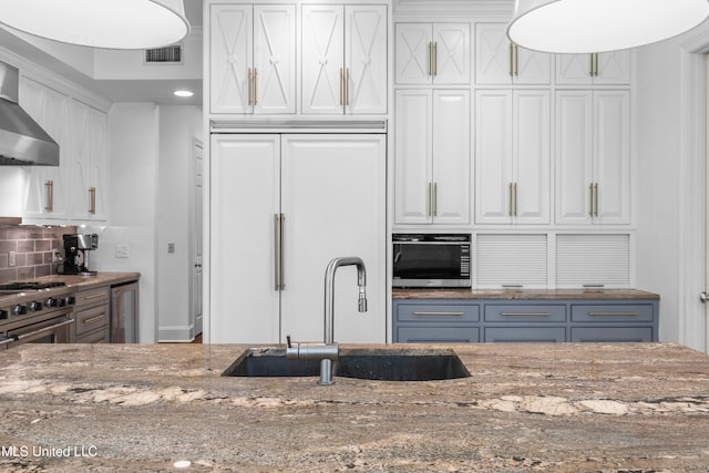 kitchen featuring white cabinets, premium appliances, sink, and stone countertops