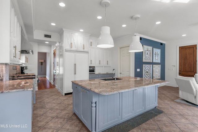 kitchen featuring backsplash, a large island, decorative light fixtures, sink, and white cabinets