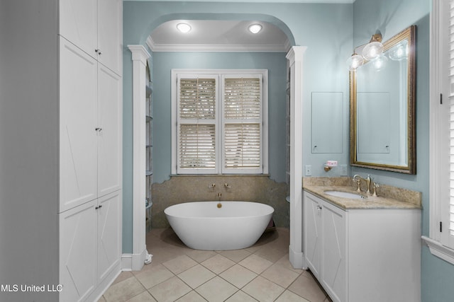 bathroom with tile patterned flooring, vanity, a bath, ornate columns, and tile walls