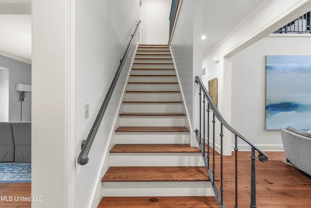 stairway featuring hardwood / wood-style floors and ornamental molding