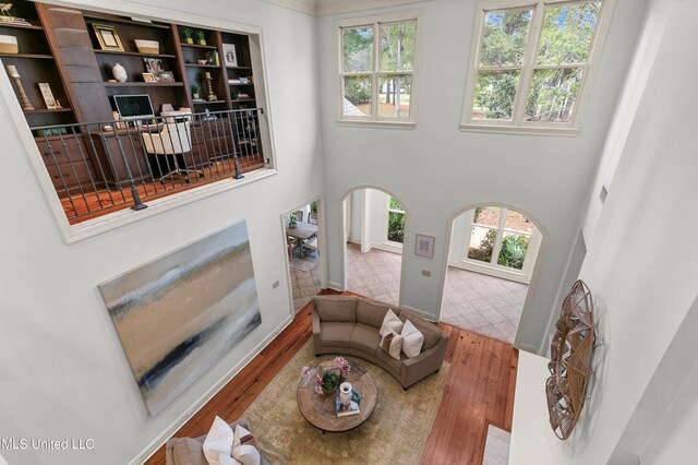 living room with a towering ceiling, hardwood / wood-style floors, and a healthy amount of sunlight