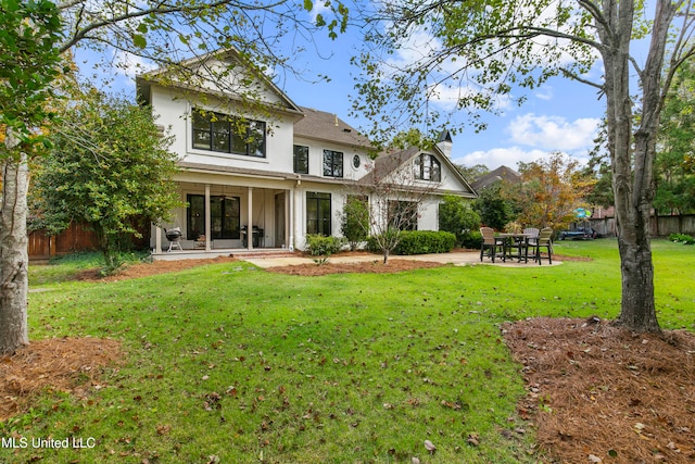 rear view of property featuring a patio and a lawn