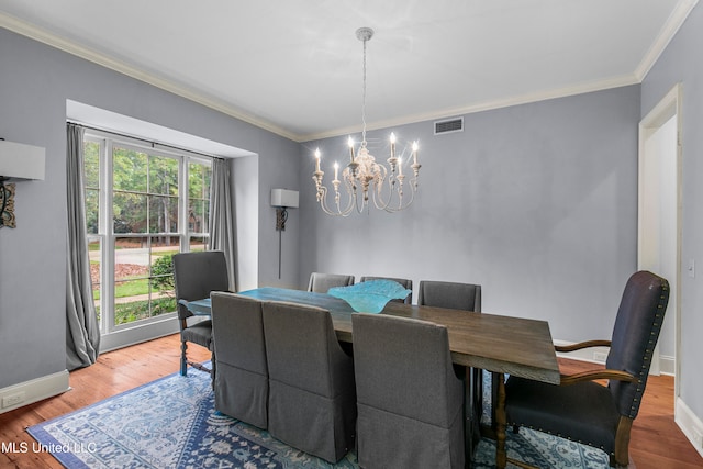 dining space featuring ornamental molding, hardwood / wood-style floors, and an inviting chandelier