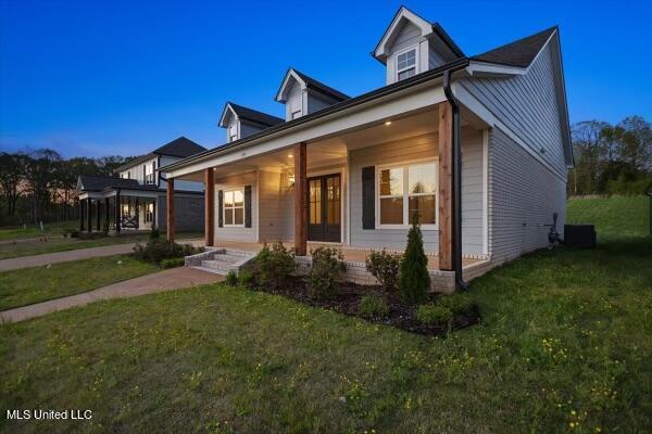 view of front of house with a yard, central air condition unit, and covered porch