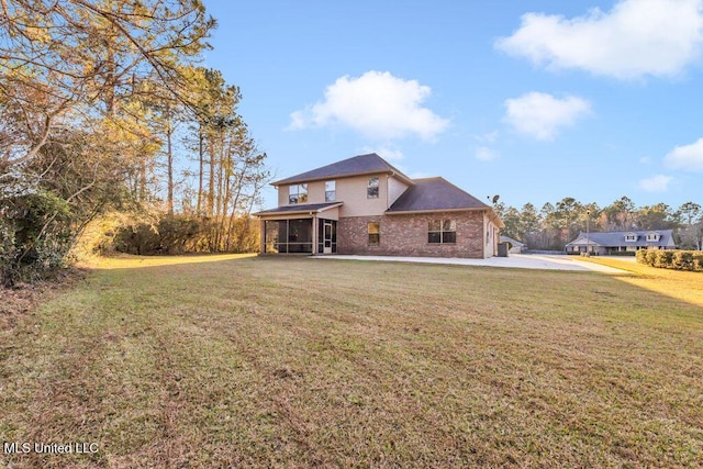 rear view of house with brick siding, a lawn, and a sunroom