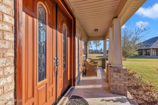 entrance to property featuring covered porch and a lawn