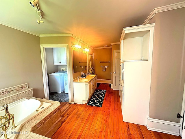 751 S Main St, Grenada, MS 38901 - bathroom with a garden tub, washer and clothes dryer, hardwood / wood-style flooring, ornamental molding, and vanity