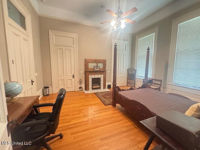 751 S Main St, Grenada, MS 38901 - bedroom featuring light wood-style floors, a tiled fireplace, a desk, and a ceiling fan