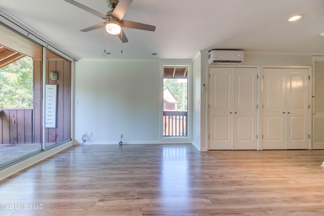 interior space featuring a wall mounted air conditioner, a wealth of natural light, light wood-type flooring, and ceiling fan