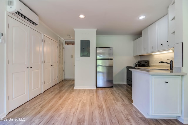 kitchen featuring sink, black / electric stove, white cabinets, light hardwood / wood-style floors, and stainless steel refrigerator