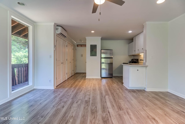 kitchen featuring an AC wall unit, ceiling fan, light hardwood / wood-style floors, white cabinets, and stainless steel refrigerator