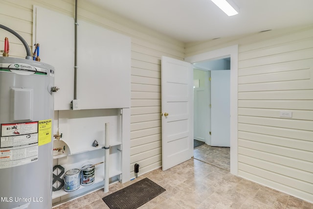 washroom featuring wood walls and electric water heater