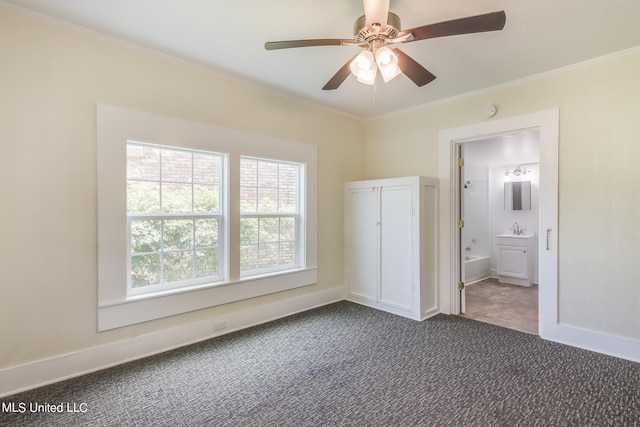 unfurnished bedroom featuring dark colored carpet, sink, crown molding, ensuite bathroom, and ceiling fan