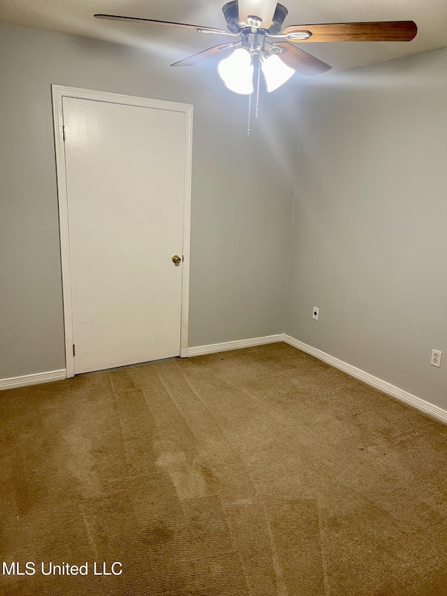 carpeted spare room with a ceiling fan and baseboards