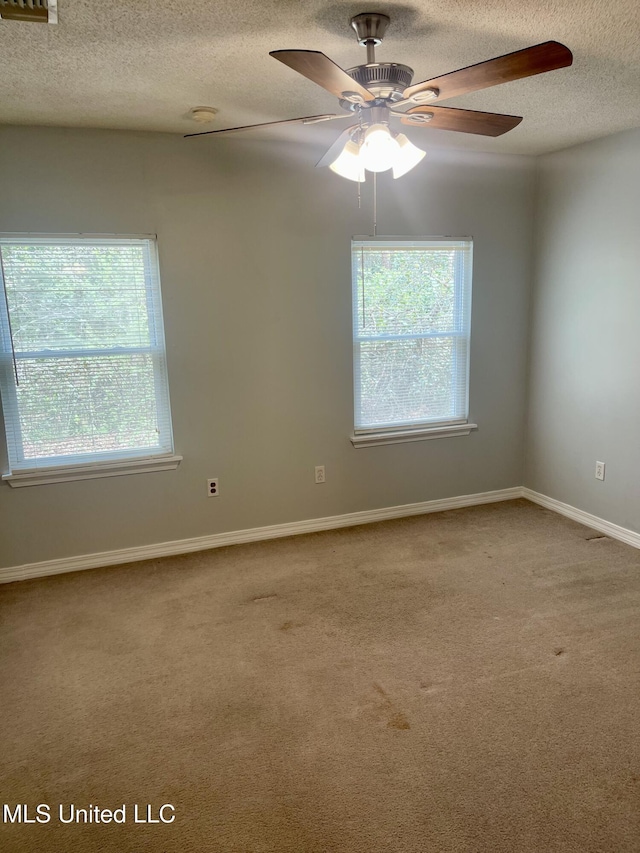 carpeted empty room featuring a textured ceiling, plenty of natural light, baseboards, and ceiling fan