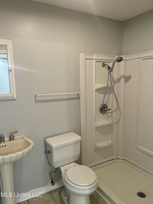 full bath with baseboards, a stall shower, a sink, tile patterned floors, and toilet