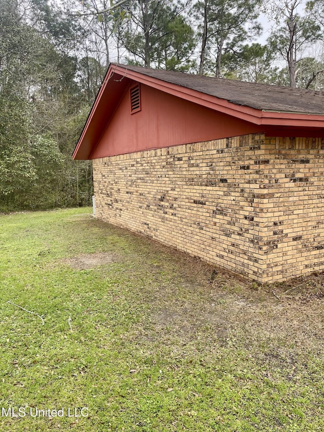 view of side of property with brick siding and a lawn