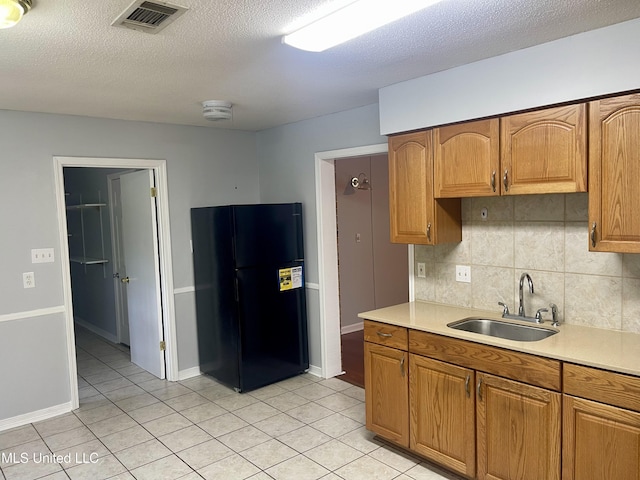 kitchen with visible vents, light countertops, freestanding refrigerator, and a sink