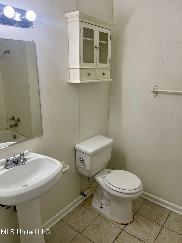 bathroom with tile patterned floors, baseboards, toilet, and a sink