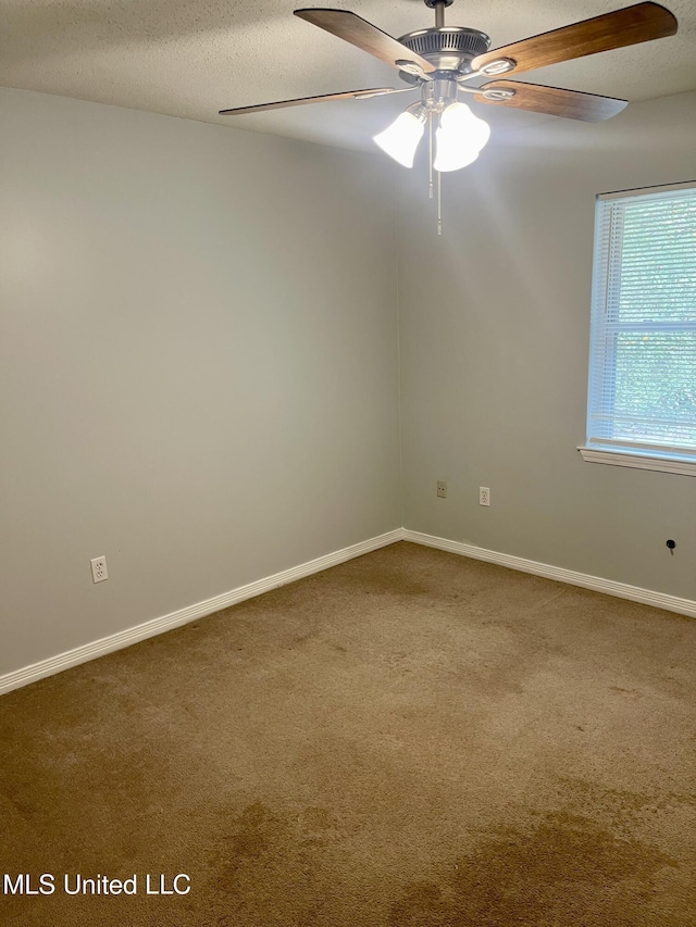 empty room with carpet flooring, a ceiling fan, baseboards, and a textured ceiling