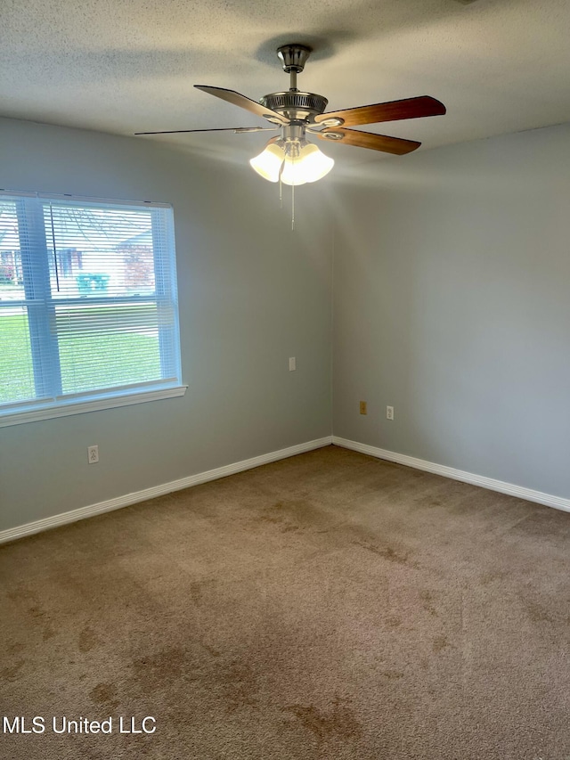 carpeted spare room featuring baseboards, a textured ceiling, and ceiling fan