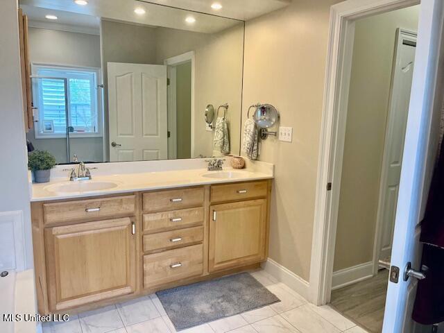 full bath with double vanity, recessed lighting, a sink, and baseboards