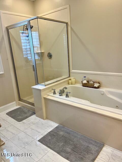 bathroom featuring marble finish floor, a tub with jets, and a shower stall