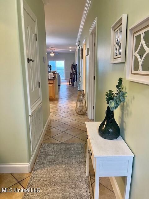 hallway featuring light tile patterned floors, ornamental molding, visible vents, and baseboards