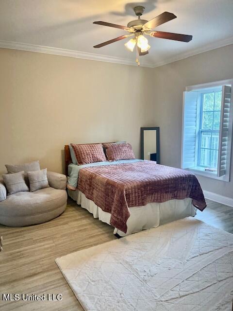 bedroom with a ceiling fan, ornamental molding, and wood finished floors